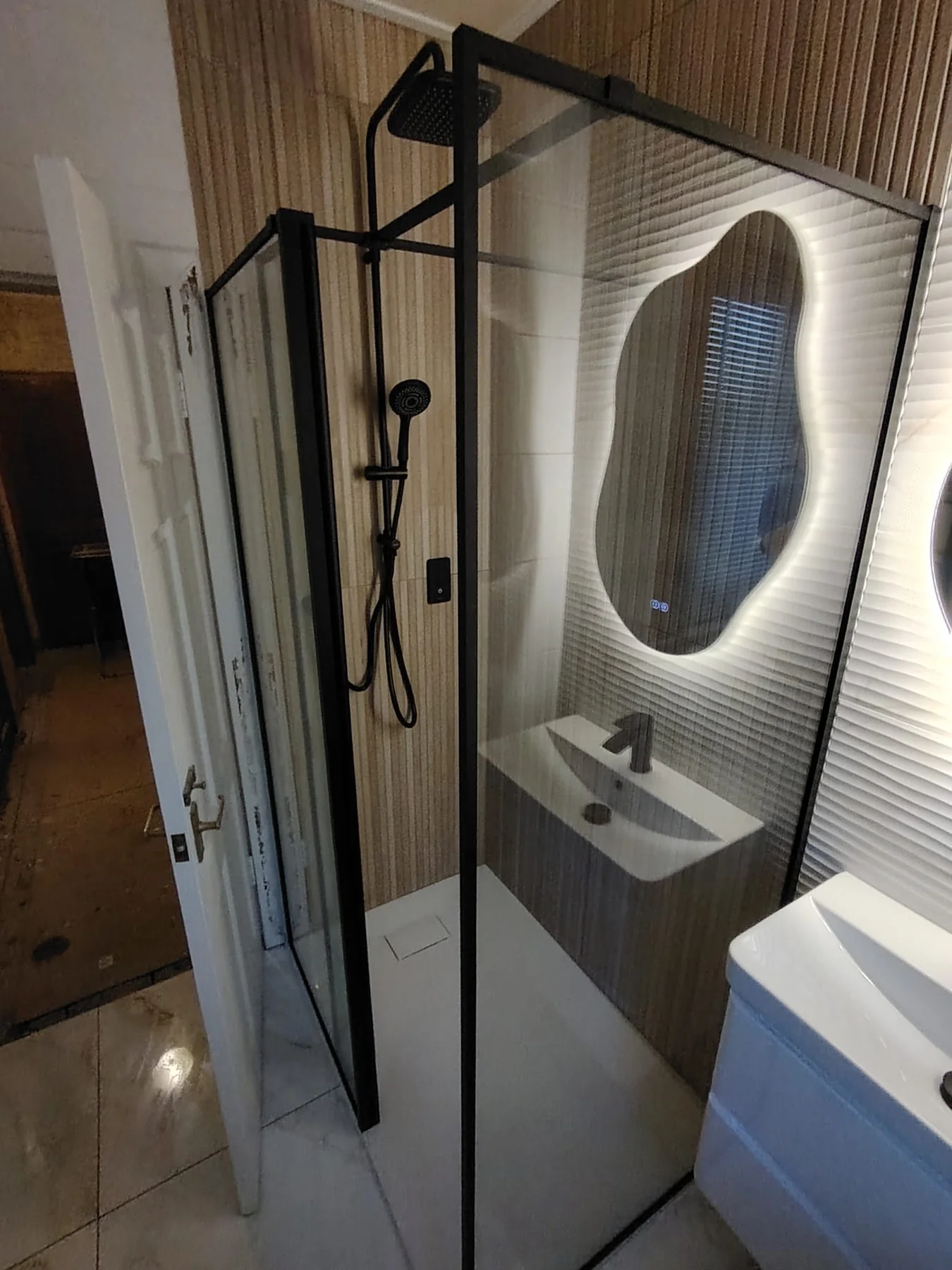 Black-framed shower enclosure against fluted timber-look tile